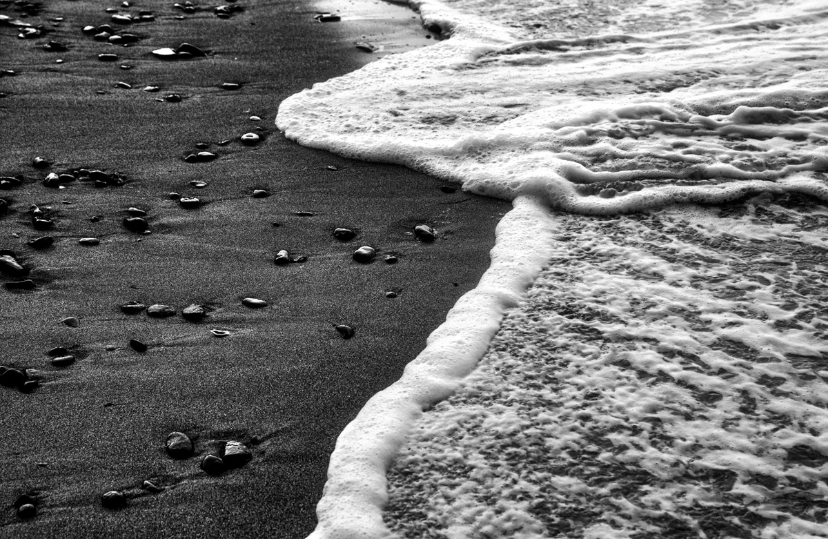 Schwarzer Strand und Brandung, Vulkanische Kiesel im Wellenschaum, Isländische Küste - Minimalistische Naturfotografie
