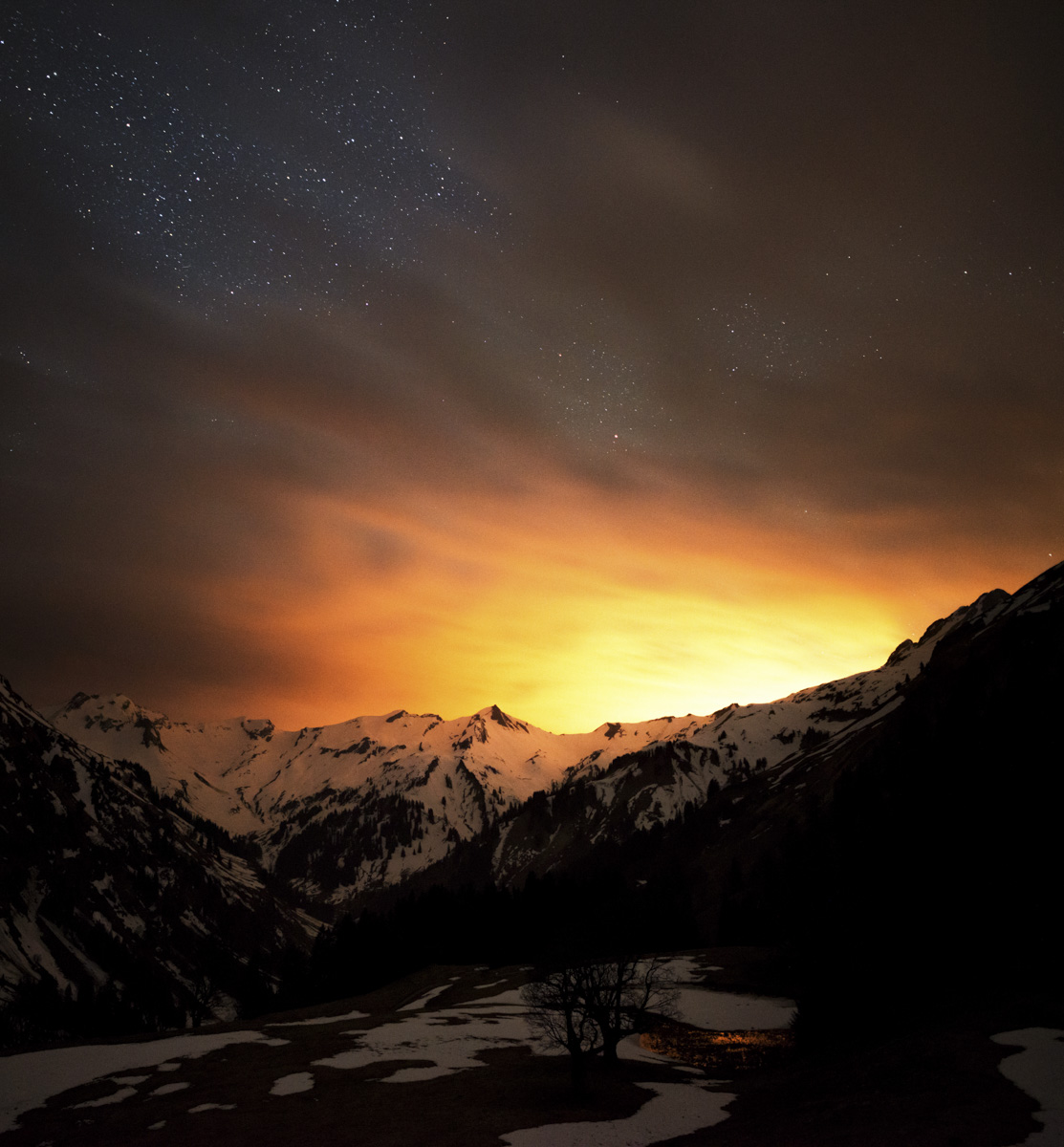 Hinterstein, Sternenhimmel über verschneiten Bergen mit goldenem Horizontlicht, Atmosphärisch - Nachtfotografie Allgäu