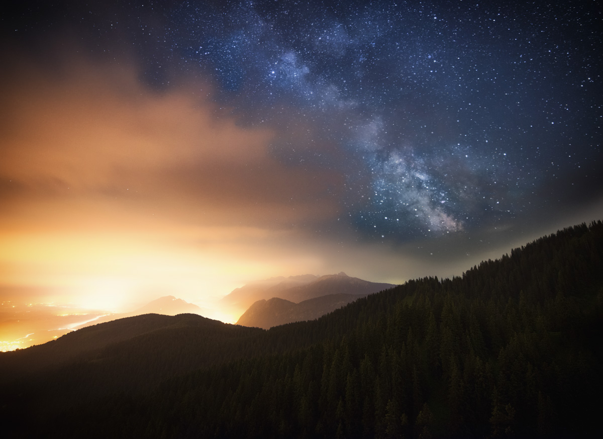 Ostallgäu, Milchstraße über Bergtal mit warmem Talleuchten, Sommernacht - Astrofotografie Allgäu