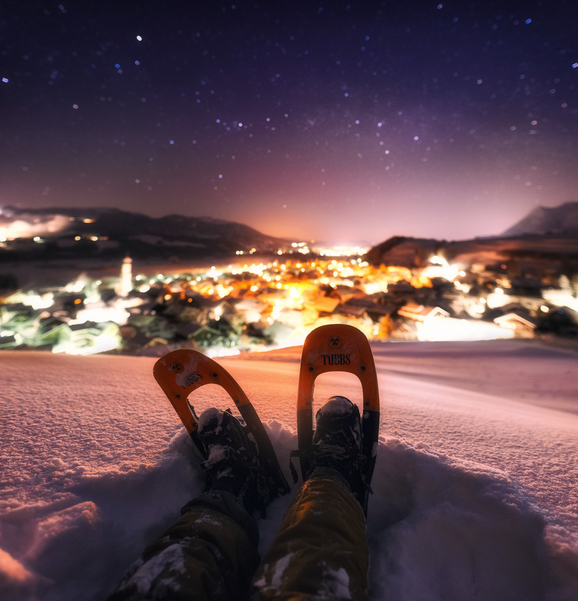 Sonthofen Altstädten, Schneeschuhwanderung unter Sternenhimmel mit Blick auf beleuchtete Stadt, Winternacht