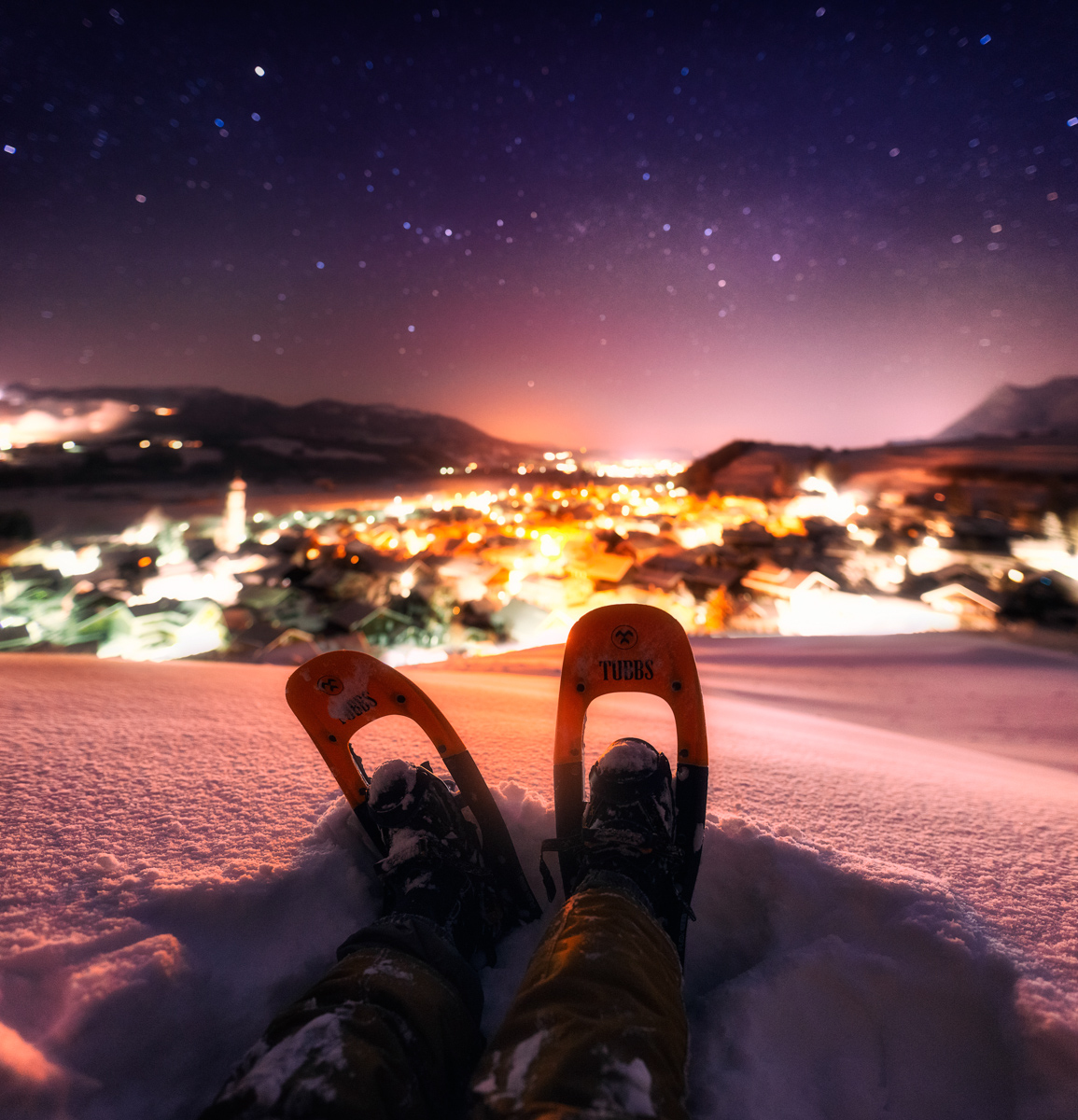 Schneeschuhwandern unter Sternen, Blick auf beleuchtetes Altstädten bei Sonthofen in Winternacht, Abenteuerliche Perspektive