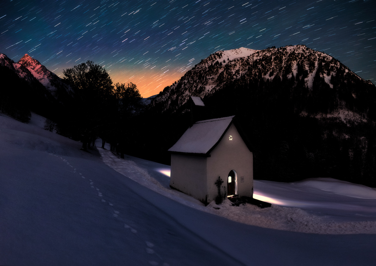 Kapelle Gerstruben unter Sternspuren, Beleuchtete Bergkapelle in verschneiter Winternacht, Besinnliche Weihnachtsstimmung