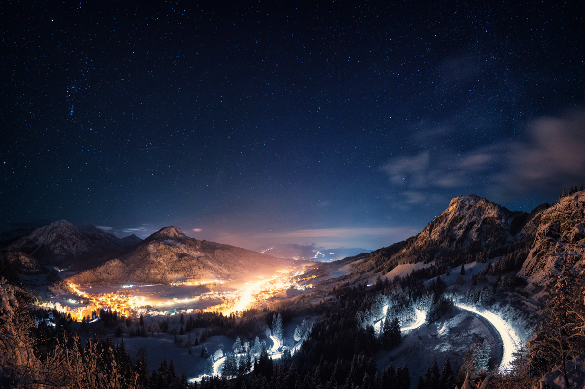 Hindelang bei Nacht vom Imberger Horn, Beleuchtete Serpentinenstraße und Sternschnuppe über Bergtal, Winterliches