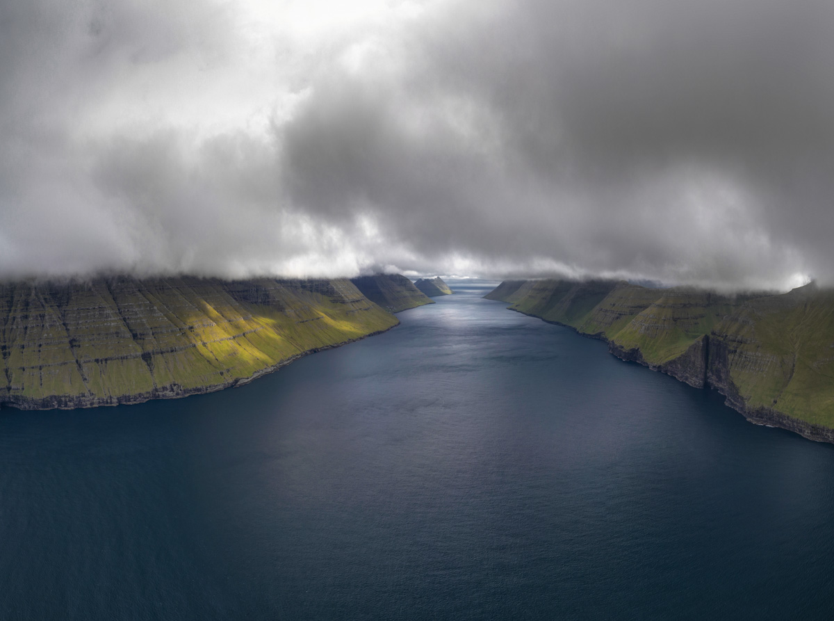 Färöer Fjordlandschaft, Symmetrischer Fjord zwischen grünen Steilklippen unter tief hängenden Wolken, Mystische Stille