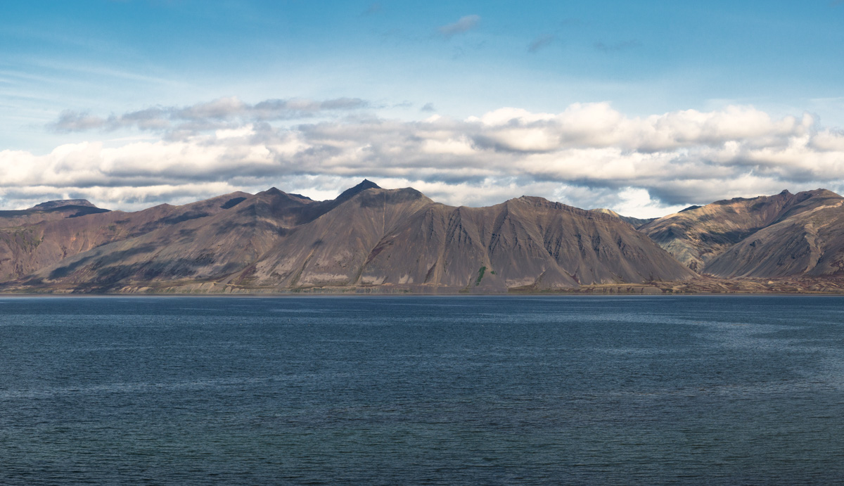 Bergpanorama am Fjord, Farbige Bergkette über blauem Meer bei Sonnenlicht, Panorama - Landschaftsfotografie Island
