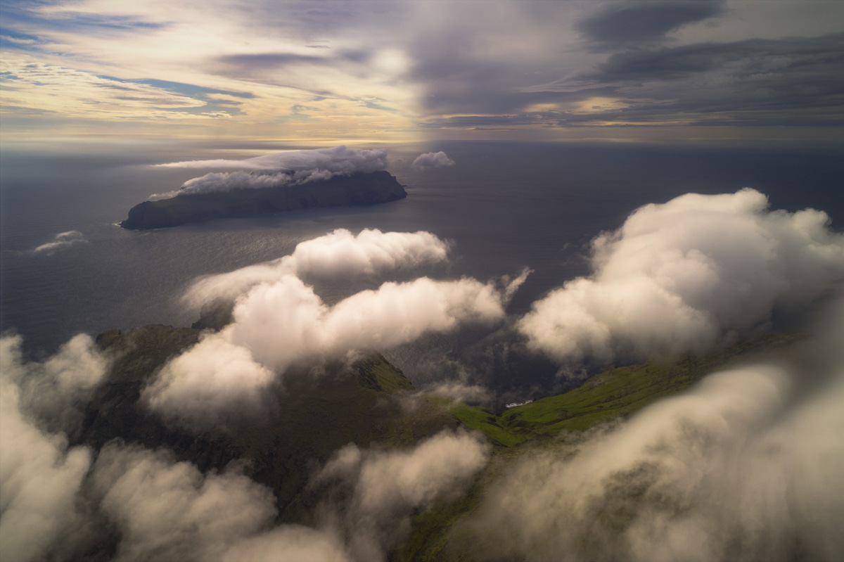 Färöer über den Wolken, Wolkenmeer zwischen grünen Inseln im Abendlicht, Traumhafte Weite - Luftaufnahme Nordatlantik