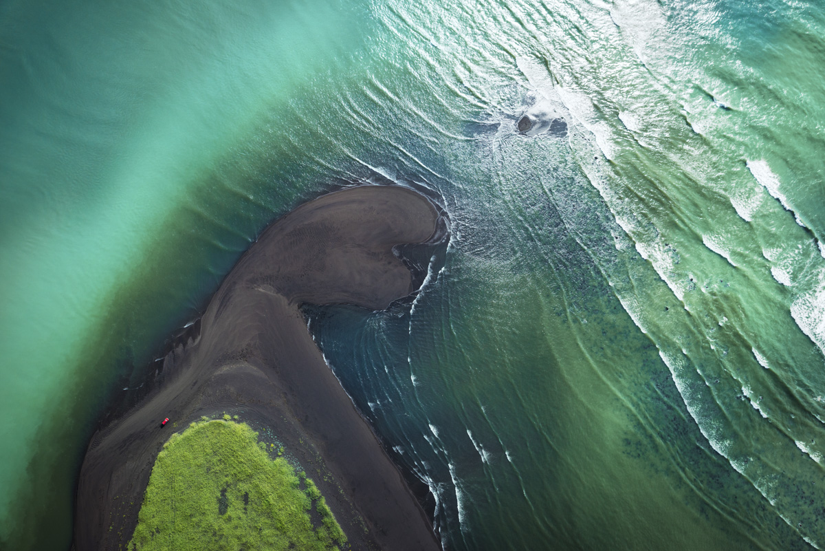 Schwarzer Strand und türkises Meer, Dramatische Küstenkurve mit Moos und rotem Auto, Minimal - Aerial Island