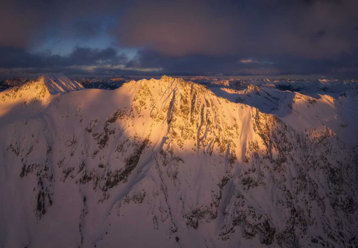 Hinterstein, Alpenglühen auf verschneitem Berggipfel unter dramatischem Wolkenhimmel, Winterabend - Bergfotografie Allgäu