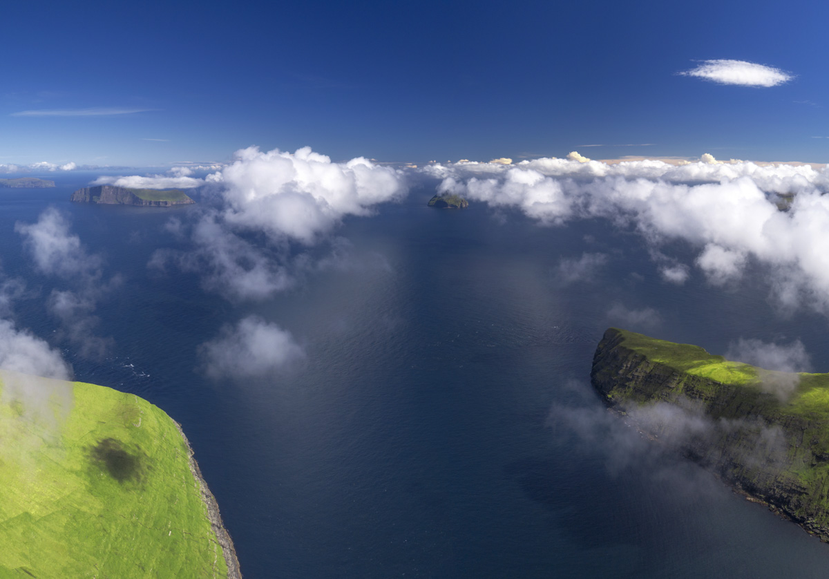 Färöer über den Wolken, Inselpanorama mit tiefblauem Ozean und grünen Klippen, Sommertag - Drohnenfotografie Nordatlantik