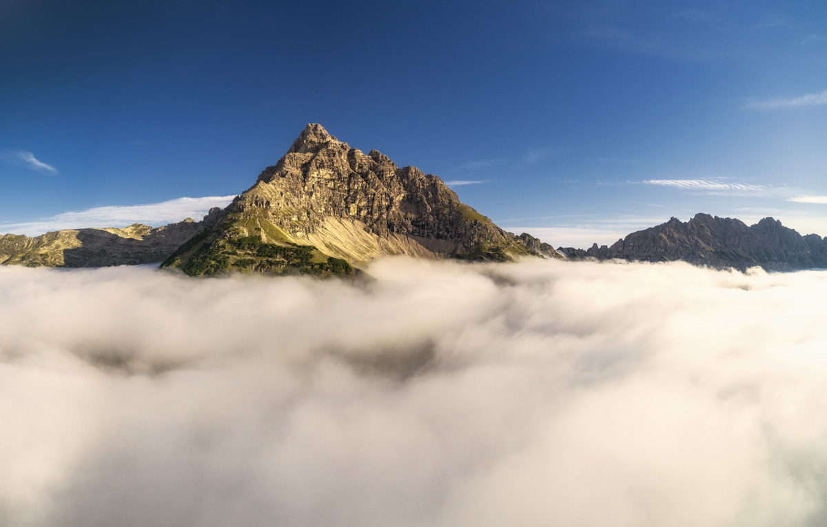 Hinterstein, Markanter Felsgipfel ragt aus Wolkenmeer in den blauen Sommerhimmel, Sommer - Bergfotografie Allgäu
