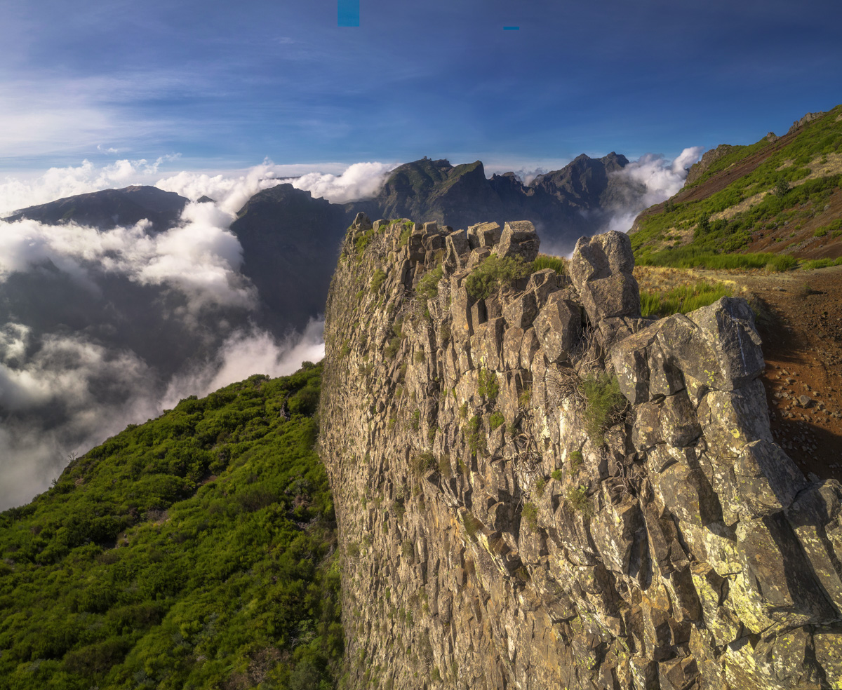 Madeira Pico do Arieiro über den Wolken, Felsige Klippe mit grüner Vegetation, Blauer Himmel über dem Wolkenmeer