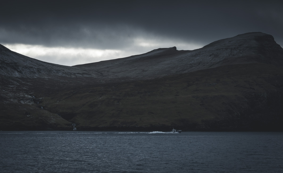 Färöer Fischerboot, Einsames Boot auf dunklem Fjord vor massivem Berg, Düstere Dramatik - Landschaftsfotografie Nordatlantik
