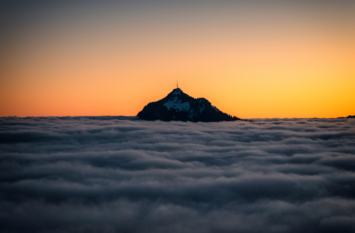 Grünten-Silhouette über dem Nebelmeer, Orangefarbener Sonnenaufgang über der Wolkendecke, Wintermorgen bei Burgberg im