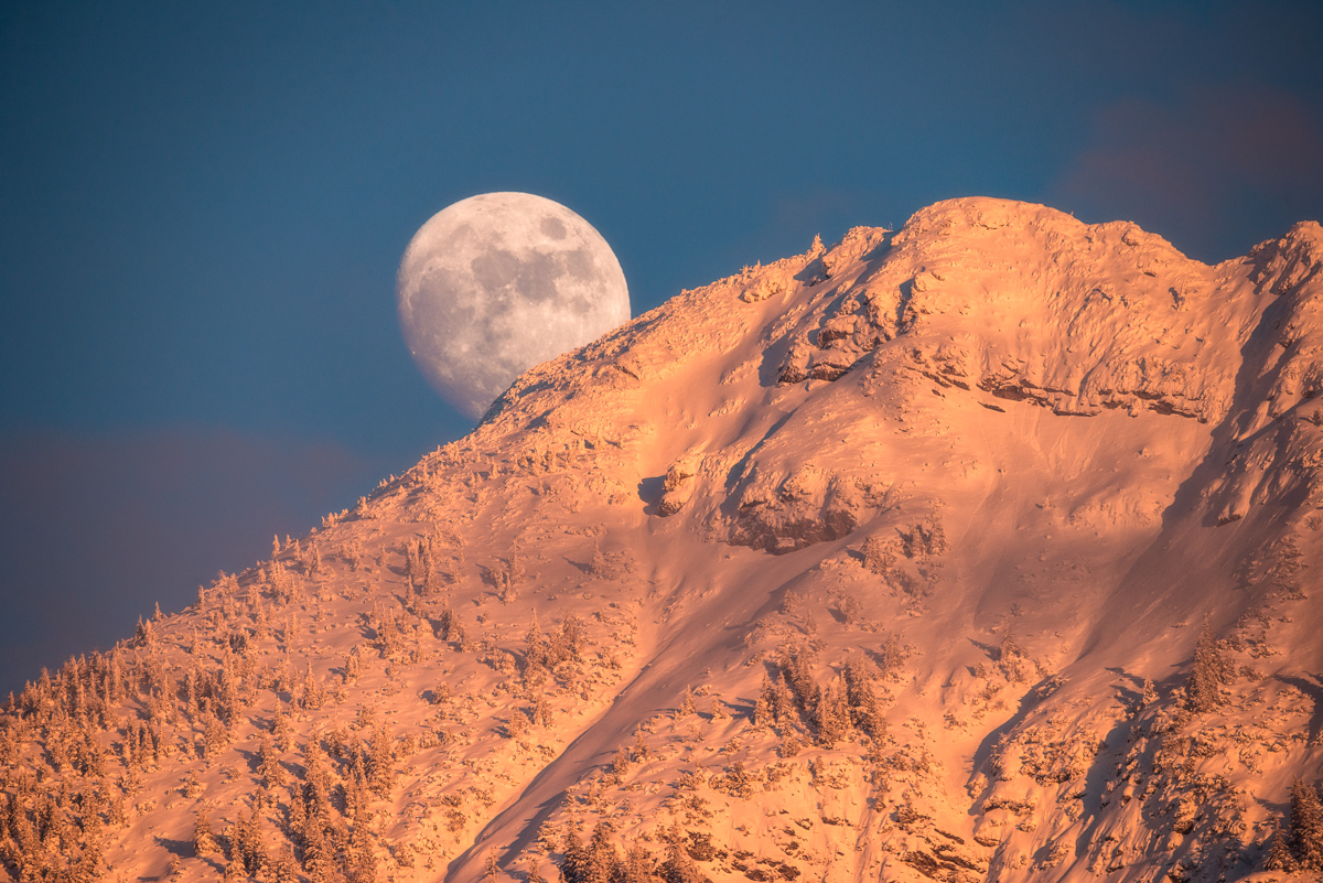 Vollmond über dem Iseler, Mondaufgang hinter verschneitem Berggipfel, Winterliches Abendlicht bei Hinterstein im Oberallgäu