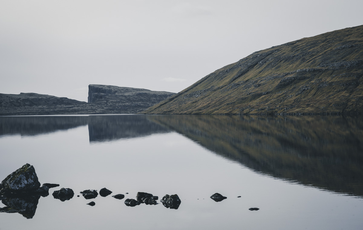 Färöer Bergsee, Stille Wasserfläche mit Felsen und Steilklippe im Hintergrund, Friedlich - Landschaftsfotografie Nordatlantik