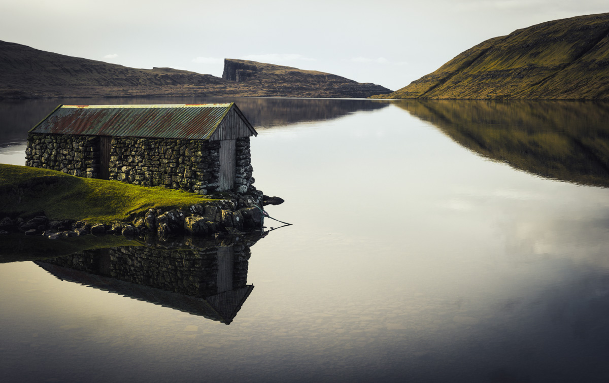 Färöer Bootshaus, Altes Steinhaus am Fjord mit Spiegelung und Steilklippe, Idyllisch - Landschaftsfotografie Nordatlantik