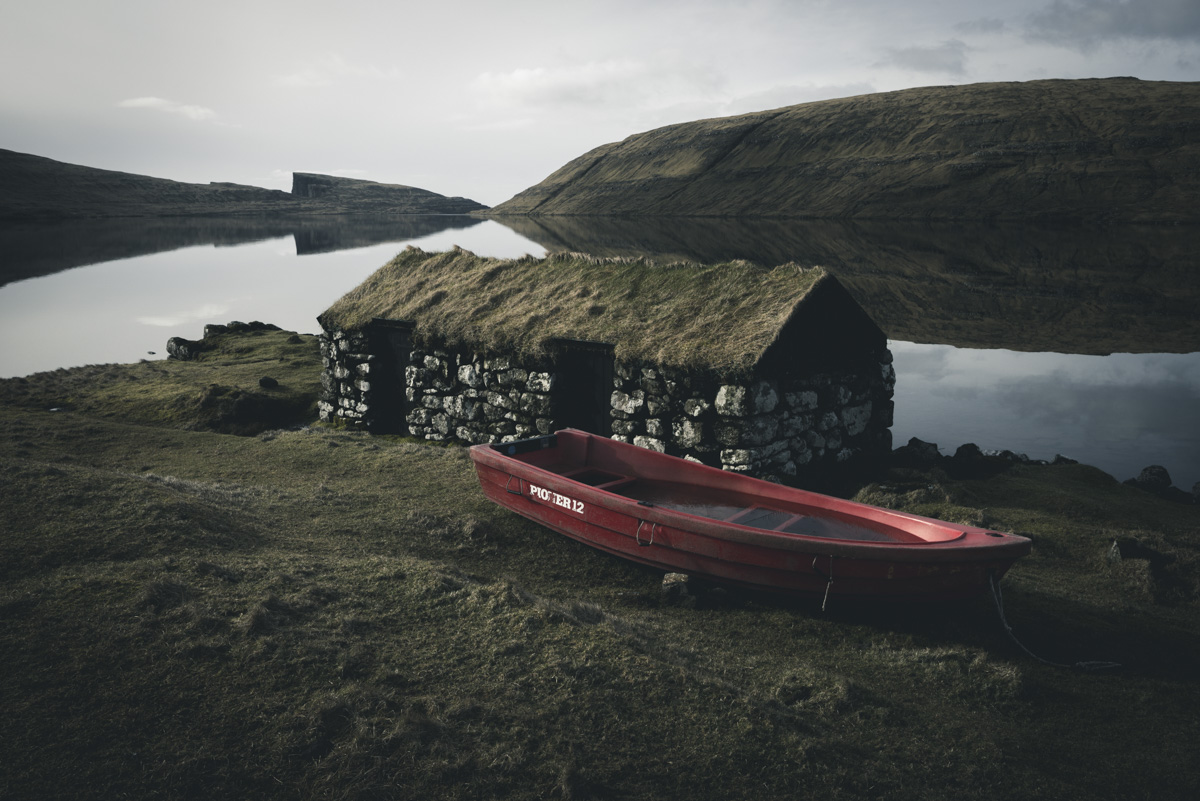 Färöer Bootshaus, Steinernes Grasdachhaus mit rotem Boot am Fjord, Atmosphärisch - Landschaftsfotografie Nordatlantik