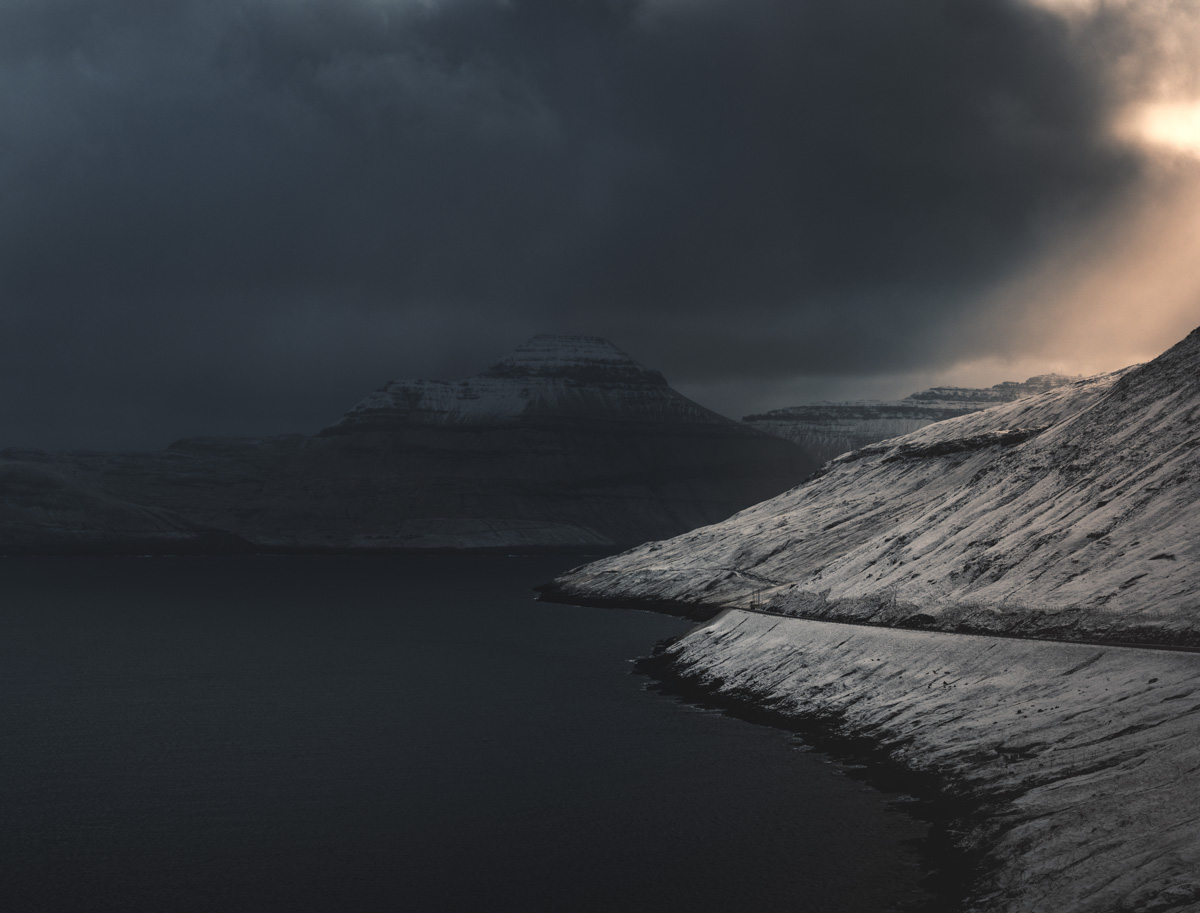 Färöer, Verschneiter Pyramidenberg über dunklem Fjord, Dramatische Winterlandschaft - Bergfotografie Färöer-Inseln