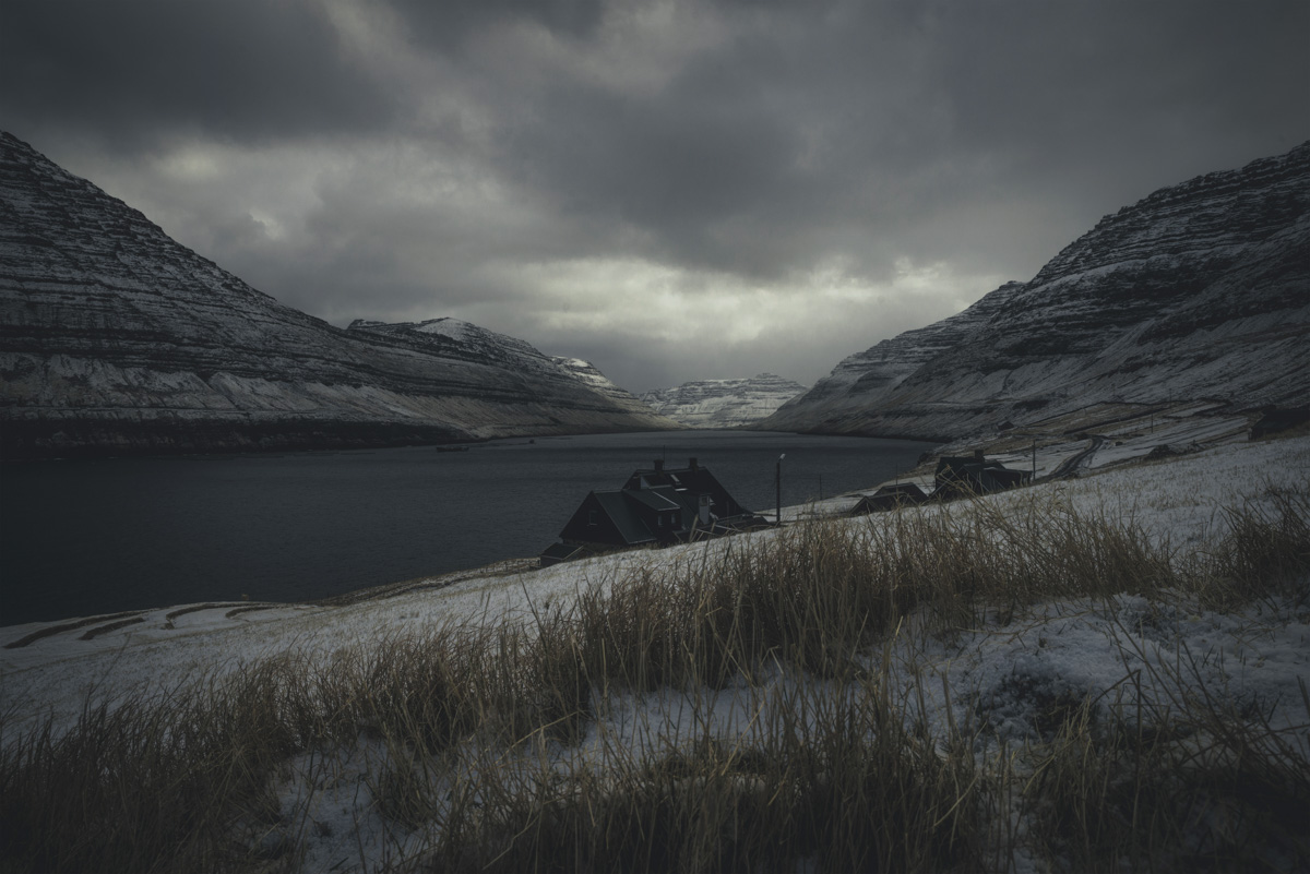 Färöer, Kleine Siedlung im verschneiten Bergtal am Fjord, Düstere Winterstimmung - Landschaftsfotografie Färöer-Inseln