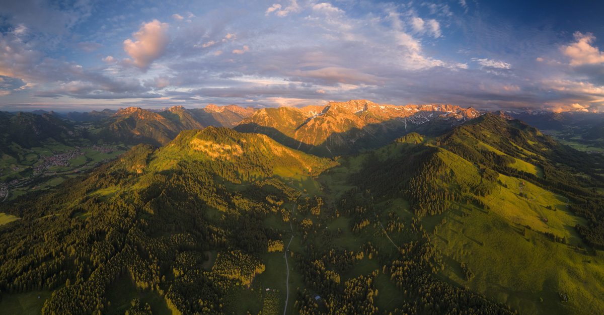 Hindelang und die Allgäuer Bergkette im sommerlichen Abendglühen, Goldenes Licht über grünen Wäldern und Gipfeln aus der