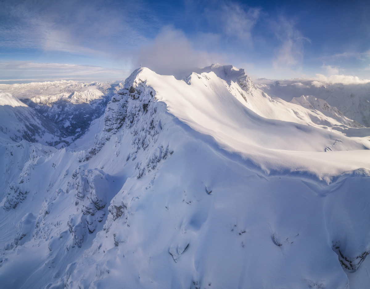 Kleiner Daumen und Pfannenhölzer am Hindelanger Klettersteig im Winterkleid, Schneeverwehungen und Gipfelkreuz unter blauem