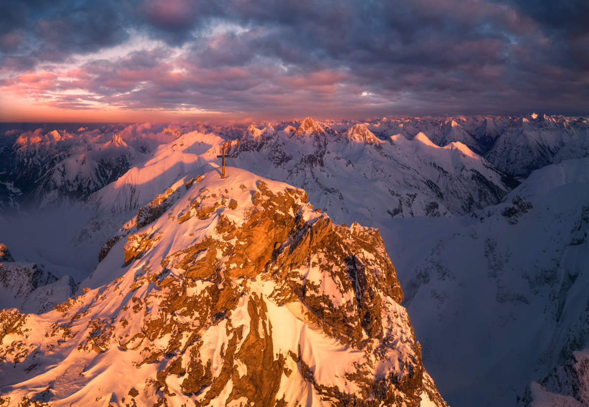 Trettach, Gipfelkreuz im dramatischen Wintersonnenuntergang, Alpenglühen über verschneiten Allgäuer Gipfeln bei Oberstdorf