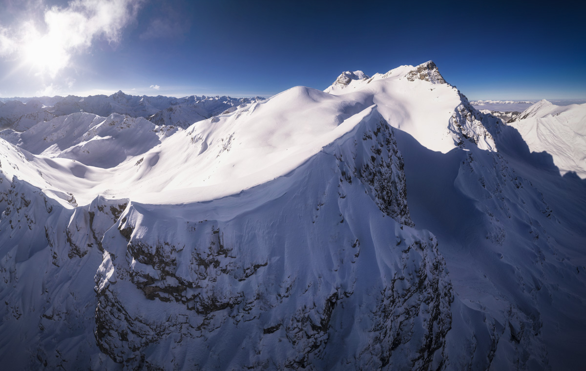 Verschneite Allgäuer Gipfelkette aus der Luft, Weiche Schneeformen und steile Felswände unter tiefblauem Himmel, Hinterstein