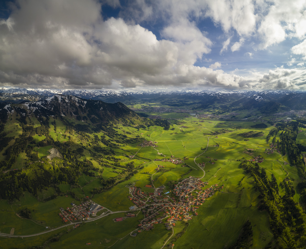 Grünten und Oberallgäuer Tal im Frühling, Saftig grüne Wiesen unter dramatischem Wolkenhimmel, Allgäu - Süddeutschland