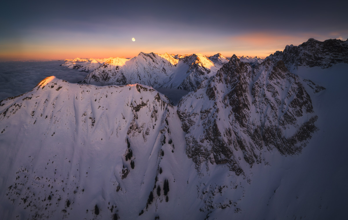 Mondaufgang über verschneiten Hochalpen bei Oberstdorf, Nebelmeer mit orange-violettem Horizont, Winterliche Dämmerung über