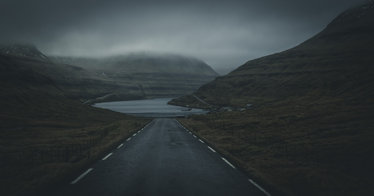 Färöer, Einsame Straße durch düsteres Bergtal zum Fjord, Roadtrip durch neblige Wildnis - Landschaftsfotografie Färöer-Inseln