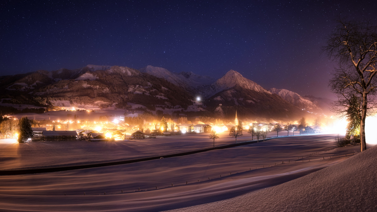 Oberstdorf bei Winternacht, Beleuchtetes Bergdorf unter Sternenhimmel, Weihnachtliche Stimmung im Allgäu