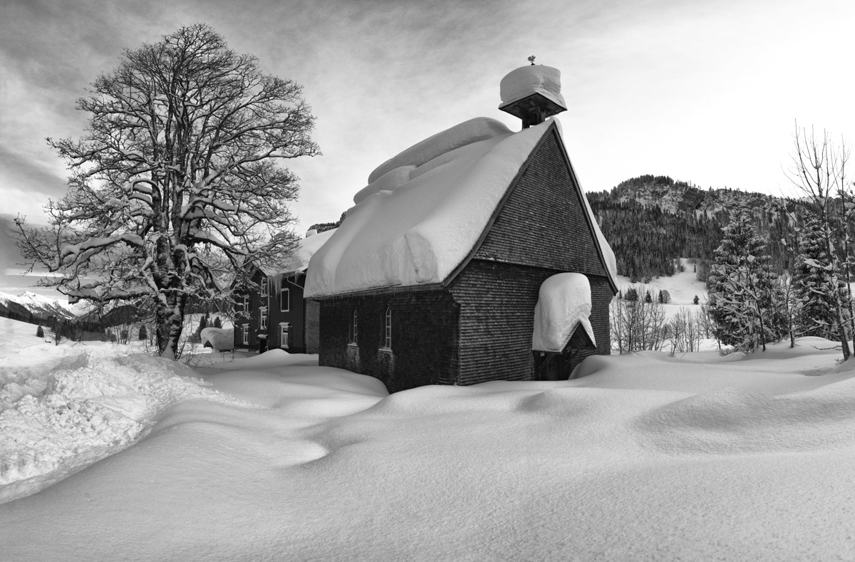 Verschneite Bergkapelle bei Oberstdorf in Schwarz-Weiß, Winteridylle mit tiefem Schnee, Zeitlose Allgäuer Winterkunst