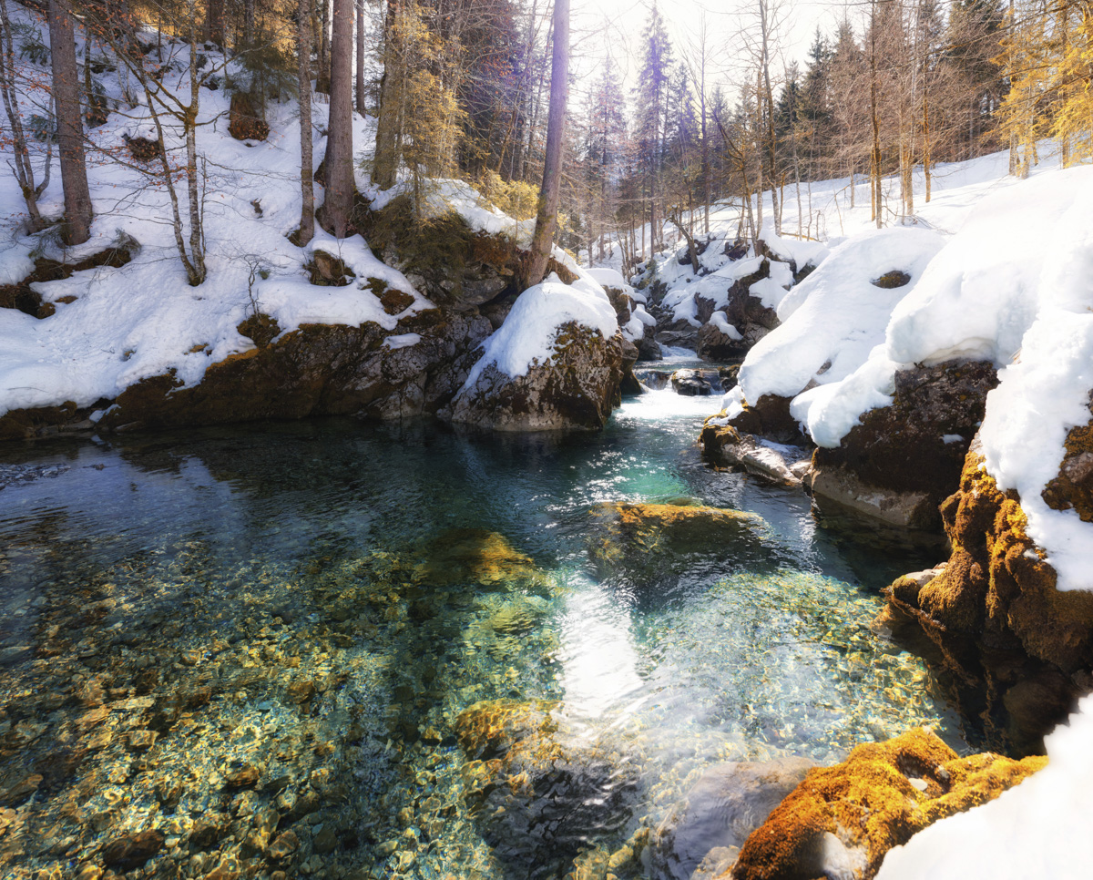 Kristallklarer Bergbach bei Hinterstein, Türkises Wasser zwischen verschneiten Felsen im Winter, Winteridylle Allgäu