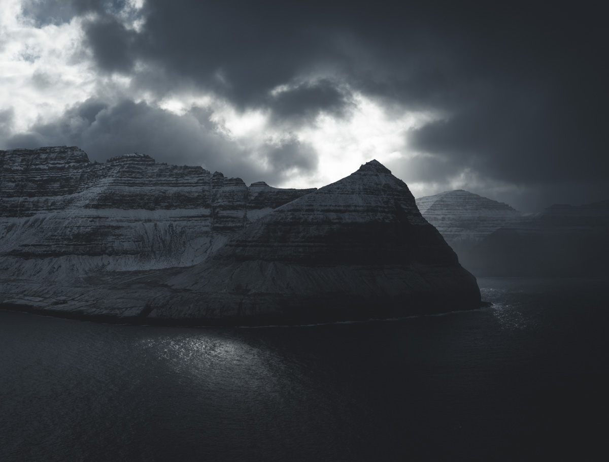Färöer Winter, Verschneite Schichtberge über dunklem Fjord im Gegenlicht, Dramatisch - Landschaftsfotografie Nordatlantik