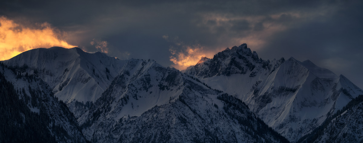 Allgäuer Bergkette Alpenglühen Wintersonnenaufgang, Oranges Licht hinter verschneiten Gipfeln unter dramatischem