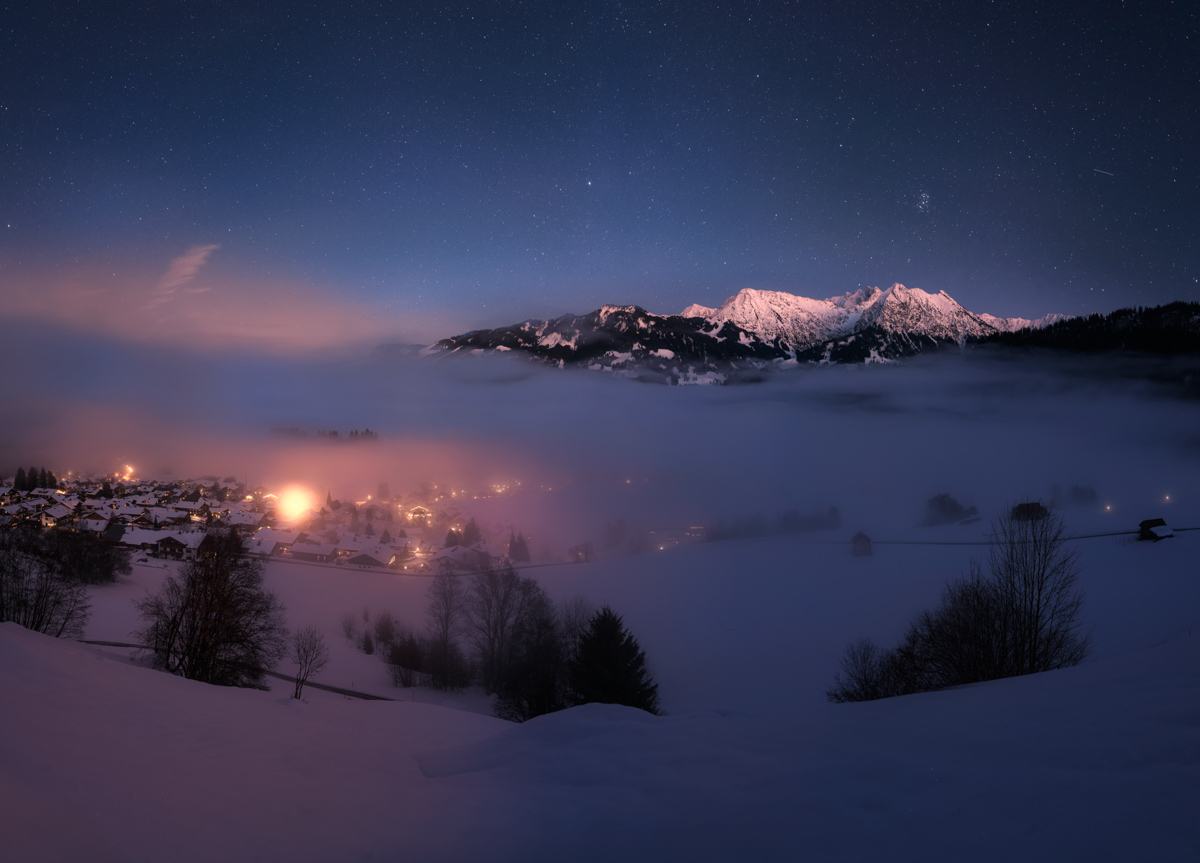 Rubihorn über Nebelmeer bei Obermaiselstein, Verschneites Bergdorf in mystischer Winternacht unter Sternenhimmel