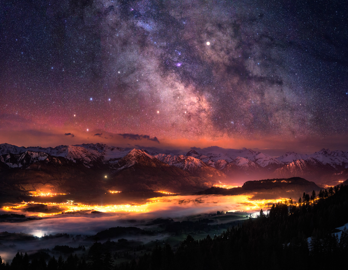 Milchstraße über dem Illertal bei Oberstdorf, Leuchtendes Bergtal mit Nebelschwaden unter kosmischem Himmel