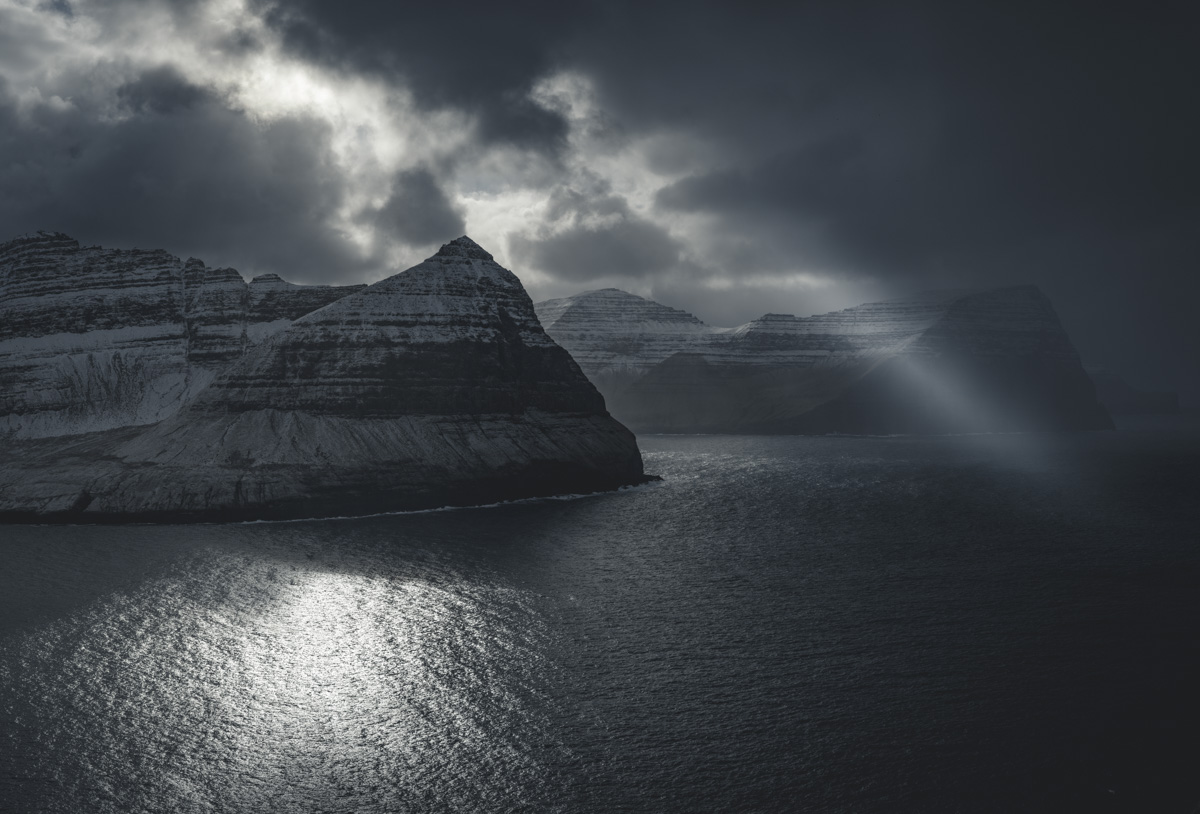 Färöer Küste Winter, Verschneite Steilküste am Fjord mit Lichtreflexion auf dem Meer, Dramatisch - Landschaftsfotografie