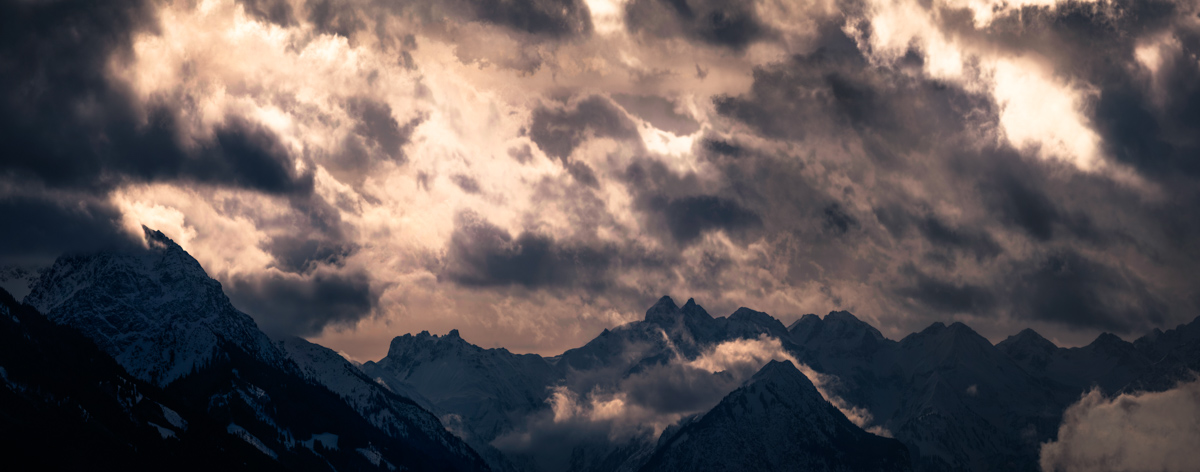 Oberstdorf, Bergsilhouetten im Wolkendrama, Orange Lichtdurchbruch am Winterabend - Bergfotografie Allgäu
