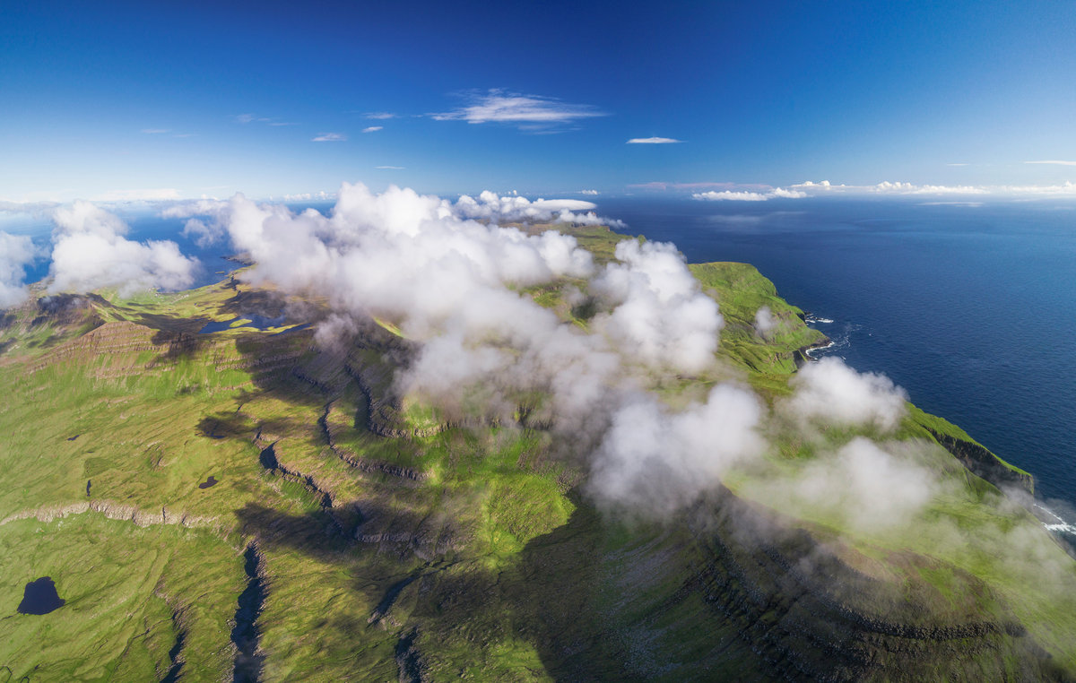 Färöer Hochplateau | Grüne Insel über den Wolken mit Erosionsrinnen und blauem Himmel | Vogelperspektive - Drohnenfotografie Färöer Inseln